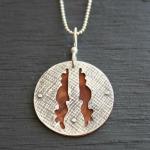 Textured and handcut sterling silver backed with red wood. $125.